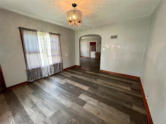 spare room featuring an inviting chandelier and dark wood-type flooring