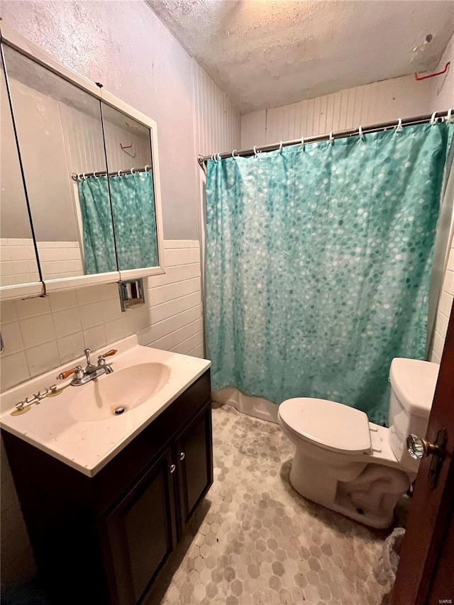 bathroom with a textured ceiling, toilet, vanity, and walk in shower