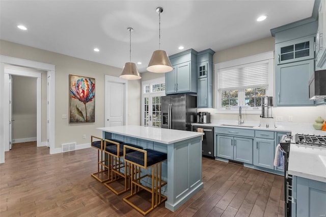 kitchen with dishwasher, a center island, light countertops, stainless steel refrigerator with ice dispenser, and a sink