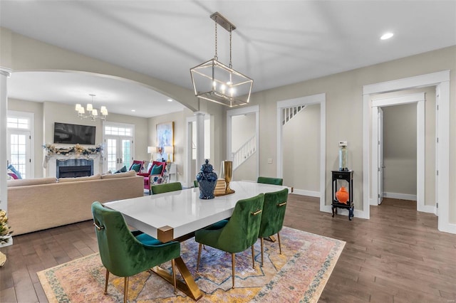 dining area with dark wood-style floors, arched walkways, stairway, and ornate columns