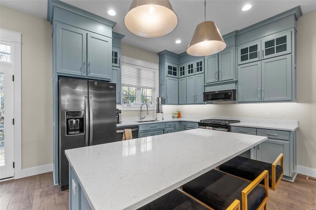 kitchen featuring a breakfast bar, light wood finished floors, appliances with stainless steel finishes, a sink, and a kitchen island