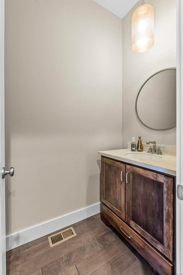 bathroom featuring visible vents, vanity, baseboards, and wood finished floors