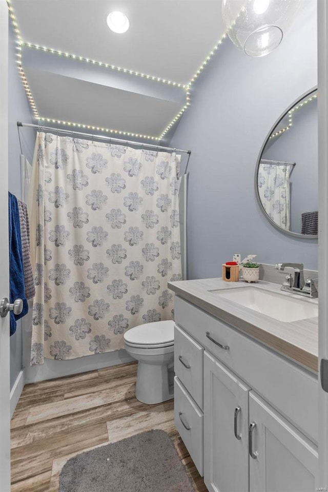 full bathroom featuring toilet, shower / bath combination with curtain, wood finished floors, and vanity