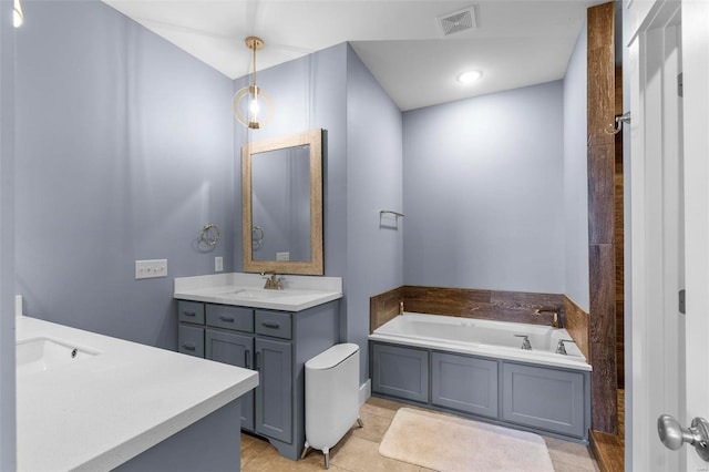 bathroom featuring a sink, a garden tub, two vanities, and visible vents