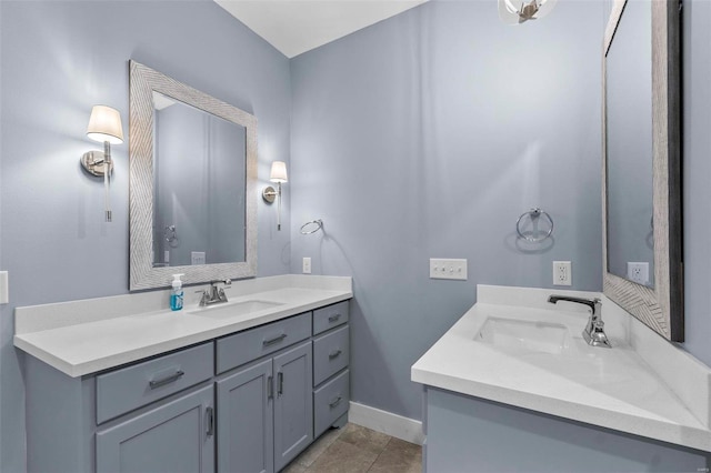 bathroom with baseboards, two vanities, and a sink