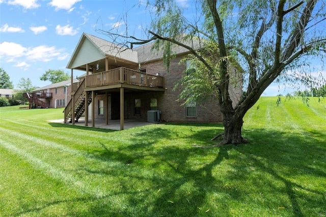 rear view of house featuring central air condition unit, a wooden deck, a patio, and a yard