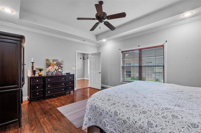 bedroom featuring dark hardwood / wood-style floors, ceiling fan, a raised ceiling, and crown molding