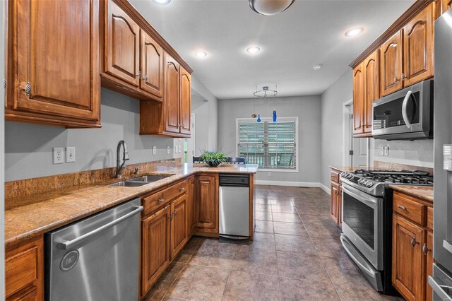 kitchen featuring appliances with stainless steel finishes, tile patterned floors, kitchen peninsula, and sink