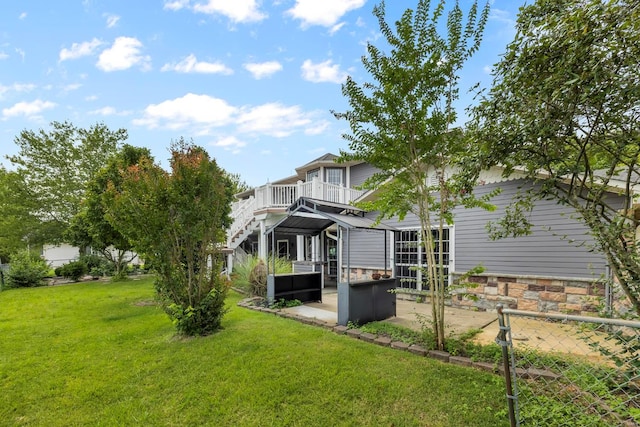 back of house featuring a balcony and a yard