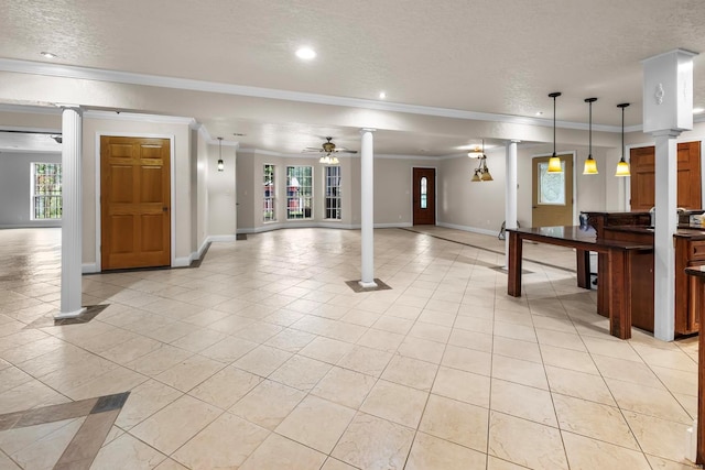 interior space with ornamental molding, ornate columns, a textured ceiling, and plenty of natural light