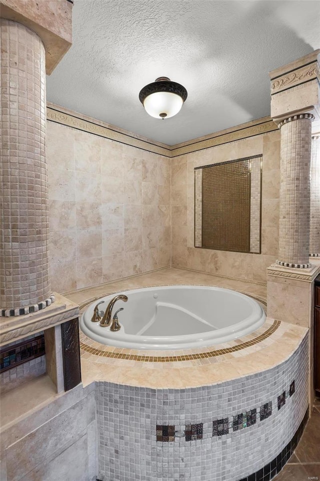 bathroom with tiled tub, tile patterned floors, and a textured ceiling