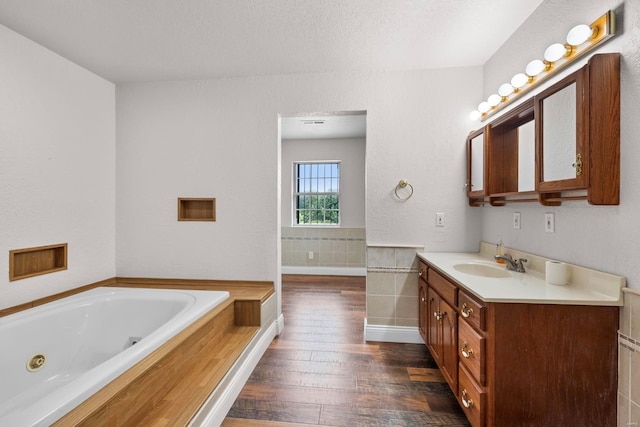 bathroom featuring a textured ceiling, vanity, wood-type flooring, and a bathtub