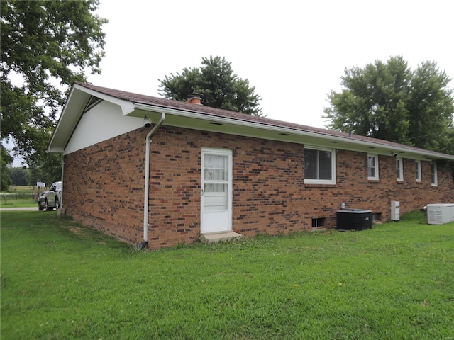 view of side of property with cooling unit and a lawn