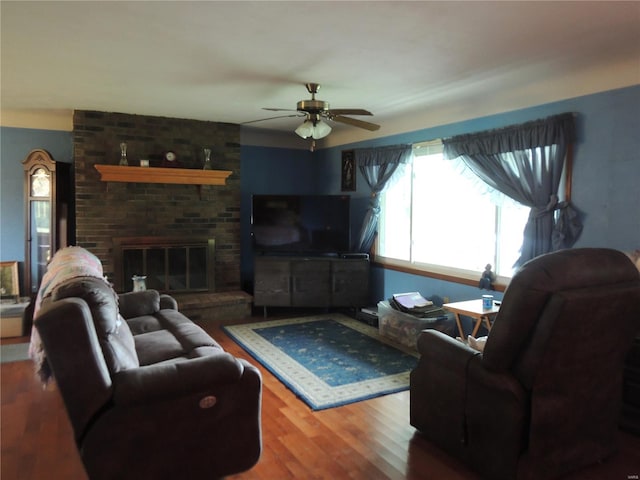 living room with ceiling fan, wood-type flooring, and a brick fireplace