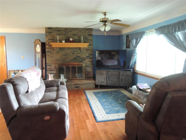 living room with ceiling fan, wood-type flooring, and a fireplace