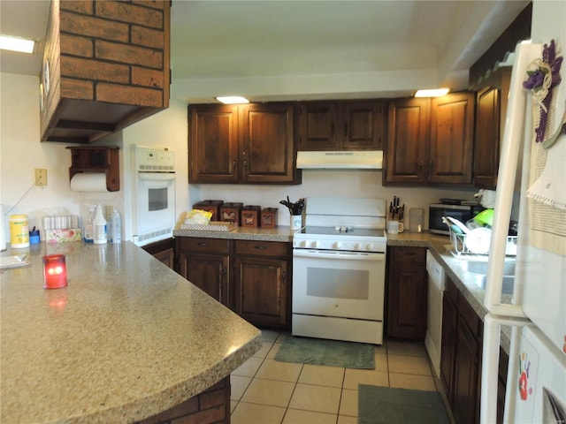 kitchen with light tile patterned floors, dark brown cabinets, and white appliances