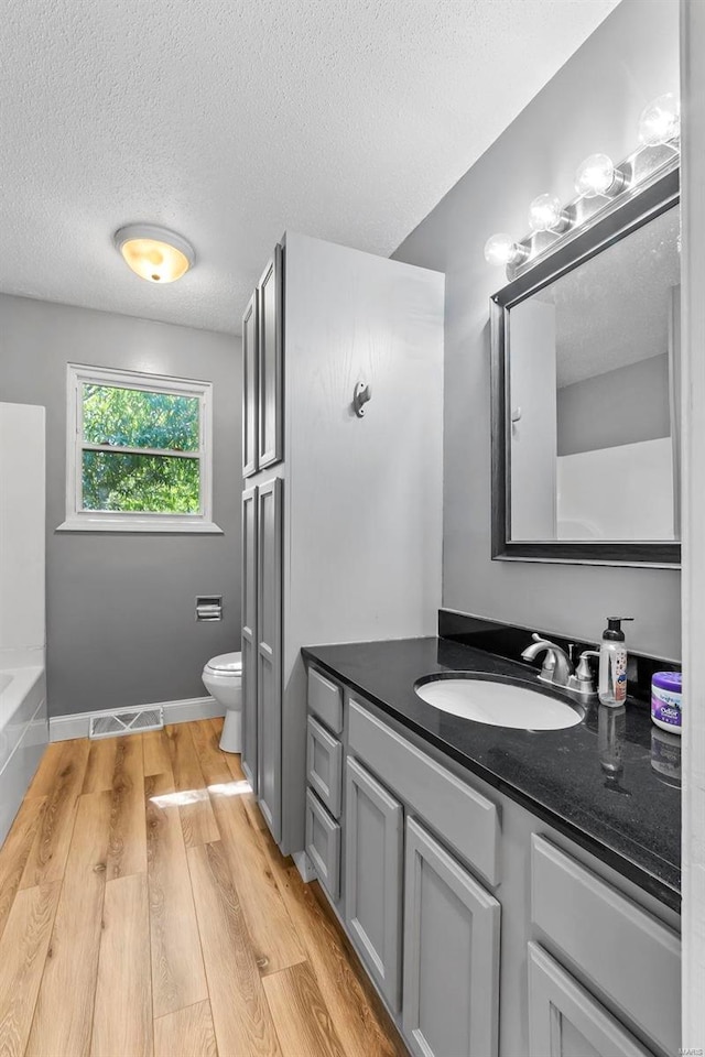 bathroom with hardwood / wood-style floors, vanity, a textured ceiling, and toilet