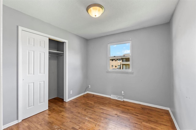 unfurnished bedroom featuring a closet and hardwood / wood-style floors