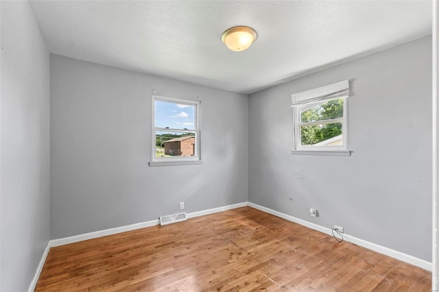 spare room with plenty of natural light, wood-type flooring, and a textured ceiling