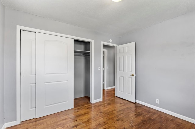 unfurnished bedroom featuring a closet, wood-type flooring, and a textured ceiling