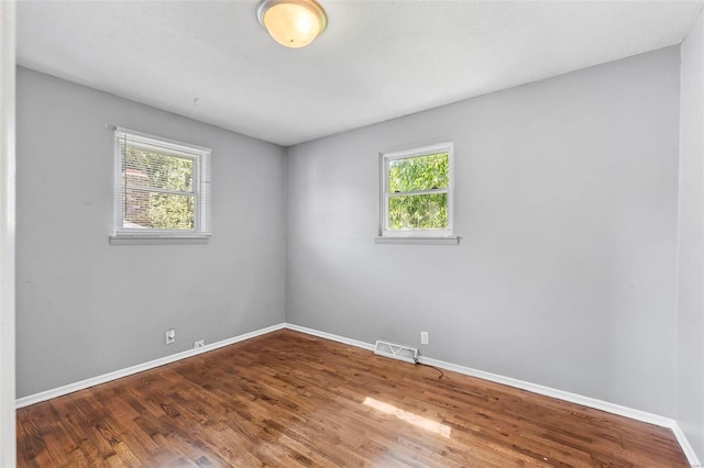 empty room with hardwood / wood-style flooring and plenty of natural light