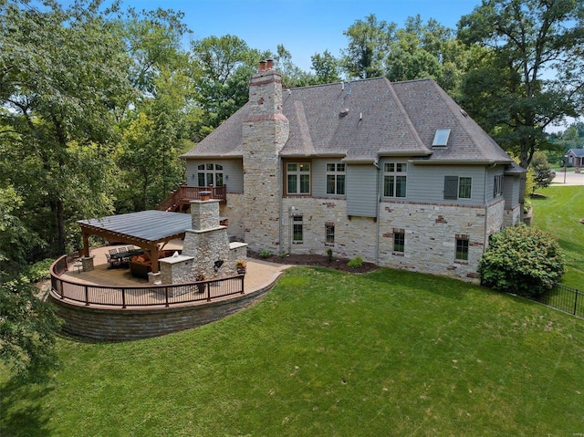 back of house featuring stone siding, a patio, a yard, a fireplace, and a chimney