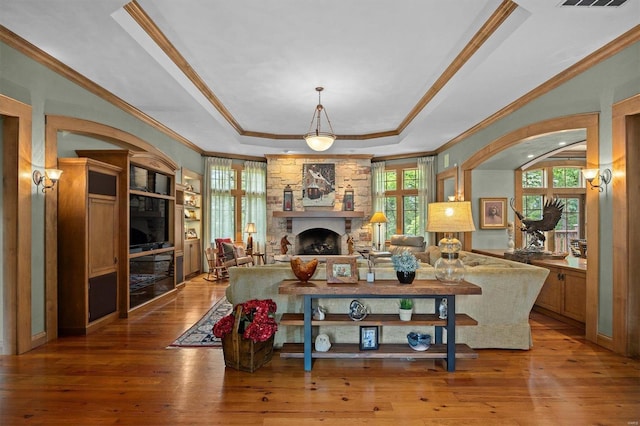 living room featuring hardwood / wood-style flooring, a fireplace, crown molding, and a raised ceiling