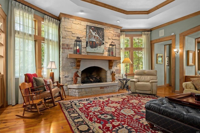 living room featuring a stone fireplace, light wood-type flooring, and crown molding