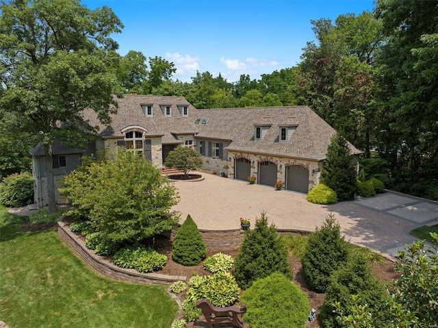 view of front of property with decorative driveway, a front yard, a garage, and stone siding