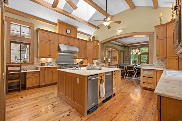 kitchen featuring ceiling fan with notable chandelier, a kitchen island with sink, beam ceiling, and light hardwood / wood-style flooring