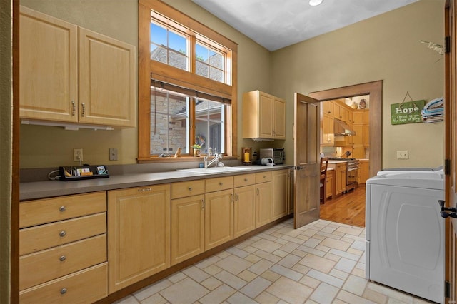 kitchen with light brown cabinetry, washer / clothes dryer, high end stove, and sink