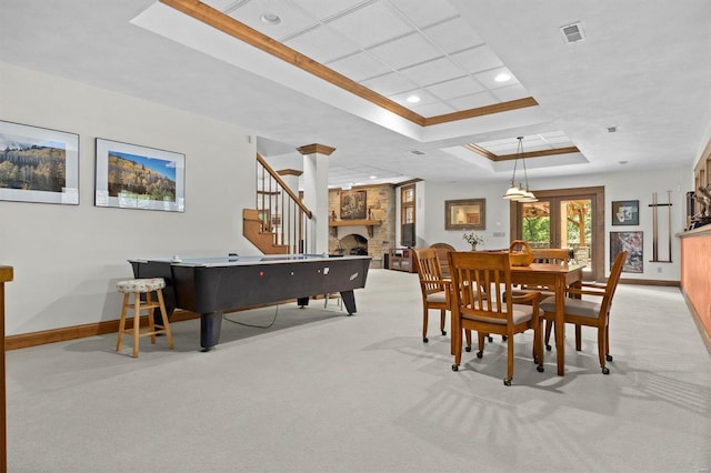 carpeted dining area featuring a raised ceiling, crown molding, and a large fireplace