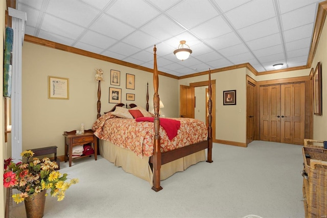 bedroom with light carpet, a closet, a drop ceiling, and ornamental molding