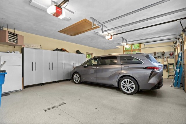 garage featuring a garage door opener and white fridge