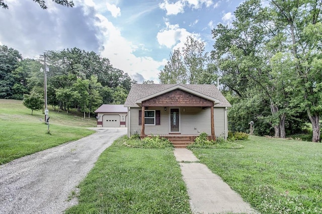 view of front of house with a garage, covered porch, an outbuilding, and a front yard