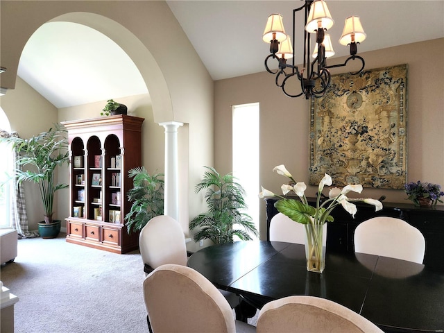 carpeted dining area featuring ornate columns, high vaulted ceiling, and an inviting chandelier