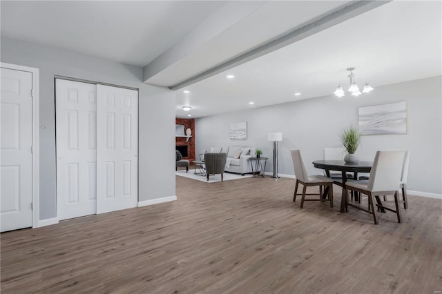 dining area with hardwood / wood-style floors, a large fireplace, and an inviting chandelier