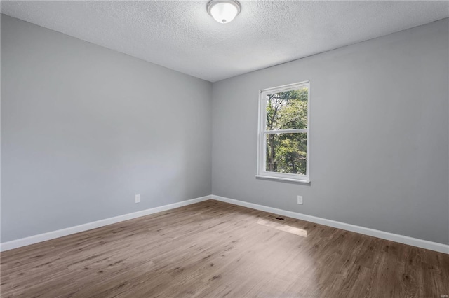 unfurnished room featuring wood-type flooring and a textured ceiling