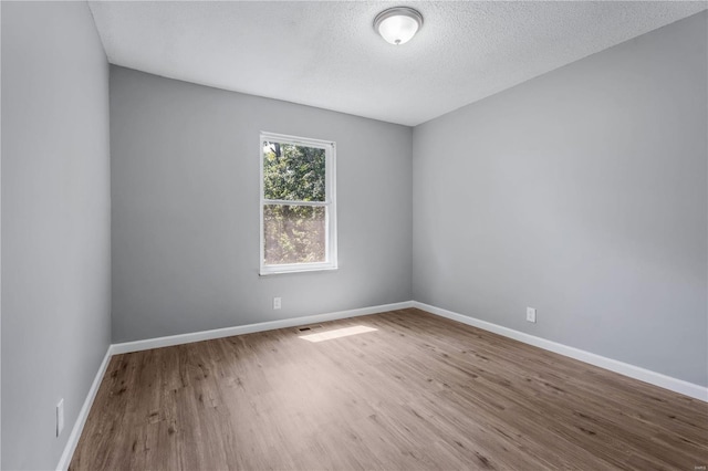 empty room with a textured ceiling and hardwood / wood-style flooring