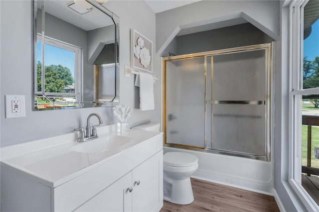 full bathroom with vanity, toilet, wood-type flooring, and shower / bath combination with glass door