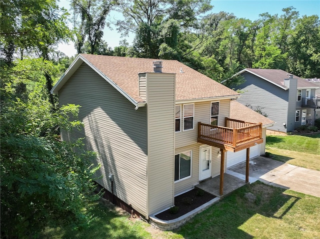 back of house featuring a garage, a yard, and a wooden deck