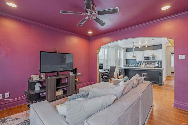 living room with light hardwood / wood-style floors, ceiling fan, and crown molding