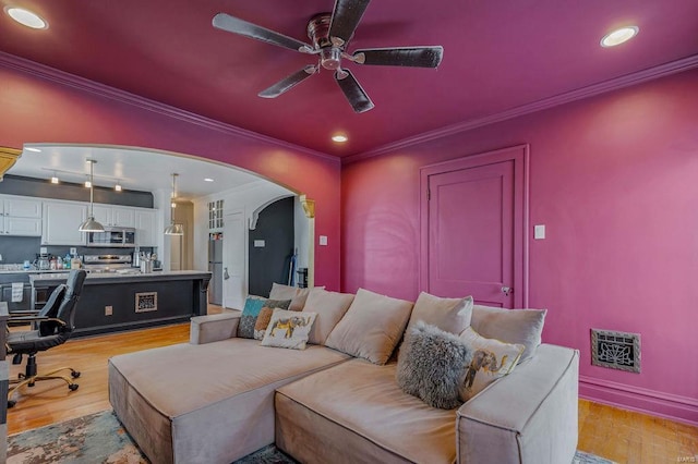 living room with light hardwood / wood-style floors, crown molding, and ceiling fan