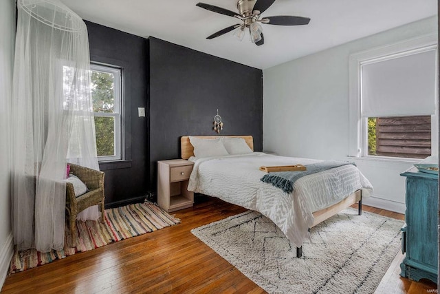 bedroom with ceiling fan, multiple windows, and hardwood / wood-style flooring