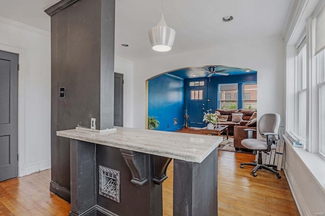 kitchen with kitchen peninsula, light hardwood / wood-style floors, decorative light fixtures, ceiling fan, and ornamental molding