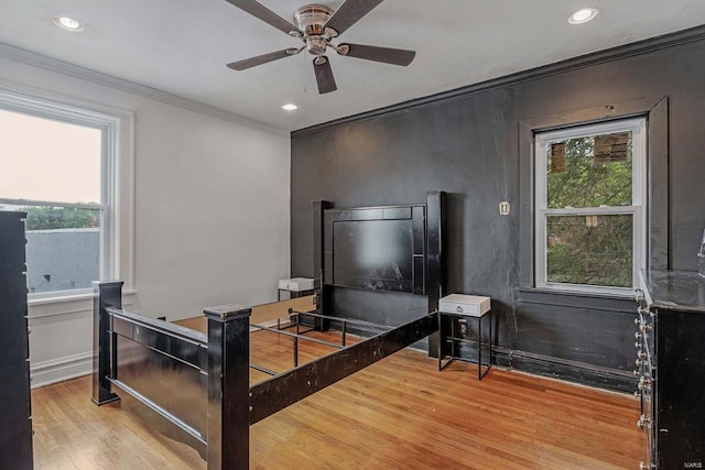 bedroom featuring multiple windows, ceiling fan, light wood-type flooring, and crown molding