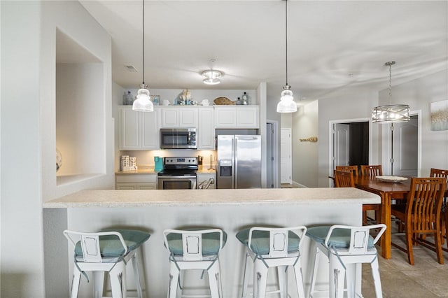 kitchen with light tile patterned flooring, stainless steel appliances, hanging light fixtures, and white cabinetry