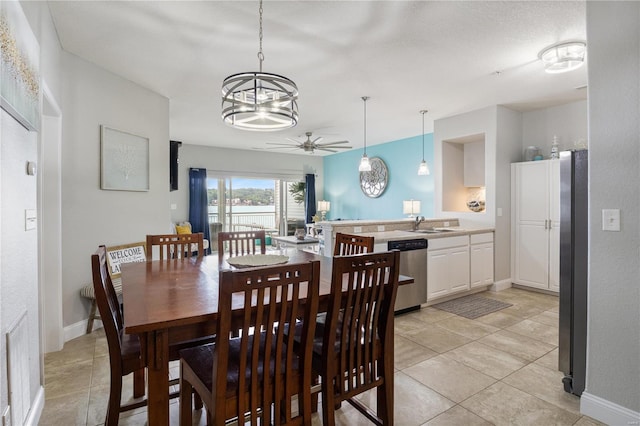 tiled dining room featuring sink and ceiling fan with notable chandelier