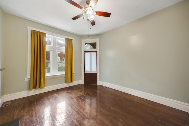 empty room featuring ceiling fan, a wealth of natural light, and dark hardwood / wood-style flooring