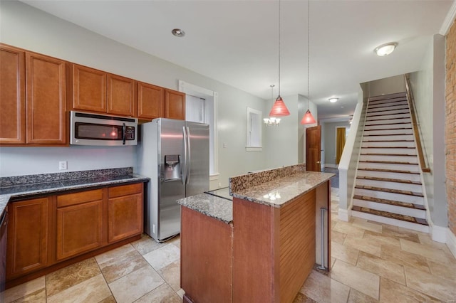 kitchen featuring stainless steel appliances, a kitchen island, dark stone countertops, and decorative light fixtures